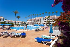 a resort swimming pool with chairs and palm trees at Parque Santiago 2 apartamento 410 in Arona