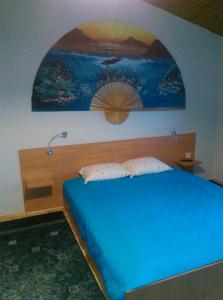 a bedroom with a blue bed with a painting on the wall at Pokoje u Jolanty in Władysławowo