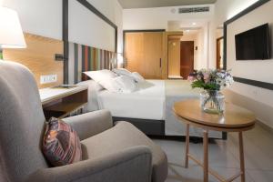 a hotel room with a bed and a vase of flowers at Hotel Gran Rey in Valle Gran Rey
