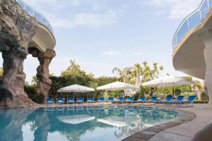 una piscina en el complejo con sillas y sombrillas en Hotel Arcobaleno, en Taureana