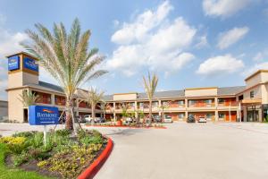 a large building with palm trees in front of it at Baymont by Wyndham Houston Hobby Airport in Houston