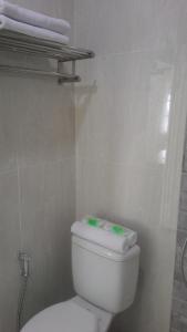 a white toilet in a bathroom with towels on a shelf at Amaranta Guest House in Batu
