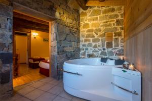 a bathroom with a tub and a stone wall at Balcon del Pirineo Rural Ordesa in Buesa
