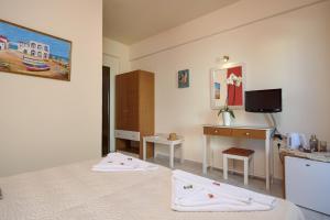 Schlafzimmer mit einem Bett, einem Schreibtisch und einem TV in der Unterkunft Antigoni in Agia Galini