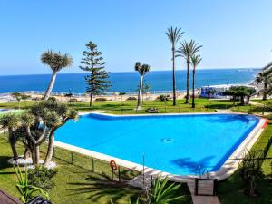 ein großer Swimmingpool mit dem Meer im Hintergrund in der Unterkunft ESTUDIO EN 1a LINEA in Torremolinos