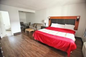 a bedroom with a large bed with a red blanket at Best Budget Inn & Suites Kamloops in Kamloops