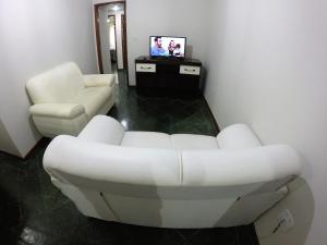 Praia Linda Hospedagem في أرايال دو كابو: غرفة معيشة مع أريكة بيضاء وتلفزيون