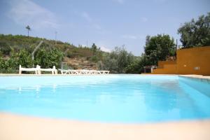 una gran piscina azul con una silla blanca en el fondo en Aldeia Oliveiras en Sobreira Formosa