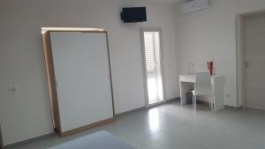 Cette chambre blanche dispose d'une porte coulissante et d'un bureau. dans l'établissement L'isola del sole, à Castelluzzo