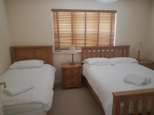 two beds in a room with a window and two lamps at Jane's Villa Free Parking in Inverness