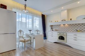 a kitchen with white cabinets and a table and a refrigerator at Bright apartment near Akropolis in Vilnius