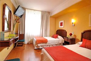 una camera d'albergo con due letti e una televisione di Hotel Gran Palace a Santiago
