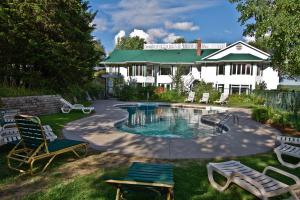 einen Pool in einem Garten mit Stühlen und einem Haus in der Unterkunft Elmhirst's Resort in Keene