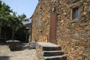 un edificio de piedra con una puerta y un banco al lado en Aldeia Oliveiras, en Sobreira Formosa