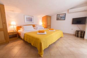 a hotel room with a bed with a yellow bedspread at Stella Maris Accommodation in Klenovica