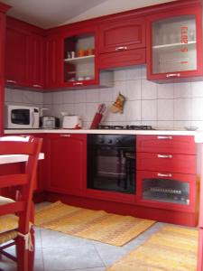 een rode keuken met rode kasten en een oven bij casa giafra in S'archittu Cuglieri