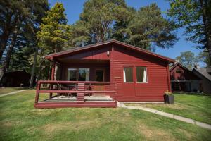 a red cabin with a picnic table in the grass at Invercauld Lodges in Ballater
