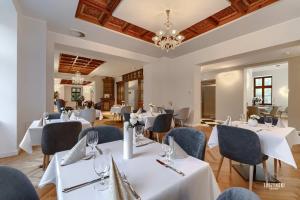 a restaurant with white tables and chairs and a chandelier at Pałac Wierzbiczany in Gniewkowo