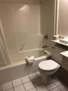 a white toilet sitting next to a bath tub in a bathroom at St. Albert Inn & Suites in St. Albert