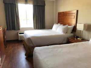 a hotel room with two beds and two lamps at St. Albert Inn & Suites in St. Albert