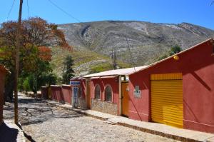 a red building with yellow doors and a mountain at Hostal Wilma in Torotoro