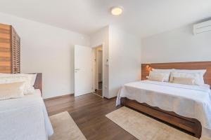 a white bedroom with two beds and wooden floors at Up27 Suites Plitvice in Plitvička Jezera