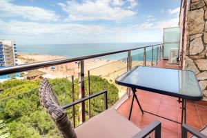 einen Balkon mit einem Tisch und Strandblick in der Unterkunft Hauzify I Apartament Rosa dels Vents in Santa Susanna