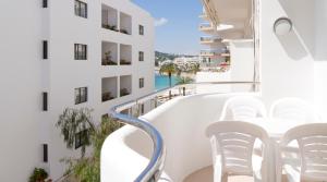 a balcony with white chairs and a view of the ocean at Apartamentos Bon Lloc in Santa Eularia des Riu