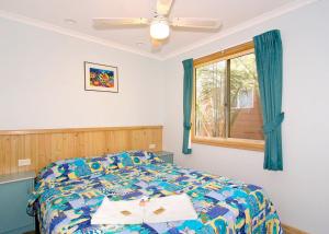 a bedroom with a bed and a window at Lorikeet Holiday Park in Arrawarra