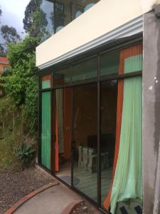 una casa de cristal con cortinas coloridas. en NUESTRA CASA - OUR HOME Suite-Studio Cuenca by A2CC en Cuenca