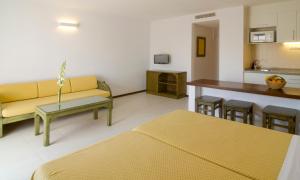 a living room with a yellow couch and a kitchen at Apartamentos Bon Lloc in Santa Eularia des Riu
