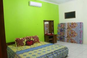 a bedroom with a bed and a green wall at Sederhana Homestay in Batukaras