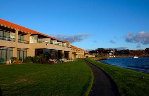 a building with a path next to a body of water at Millennium Hotel & Resort Manuels Taupo in Taupo