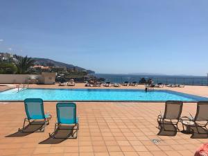 um grupo de cadeiras sentadas ao lado de uma piscina em Apartamentos do mar 303 no Funchal