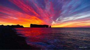 a sunset on the beach with a colorful sky at Hôtel-Motel Vagues Vertes in Perce
