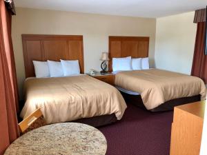 a hotel room with two beds and a table at Huntsville Inn in Huntsville