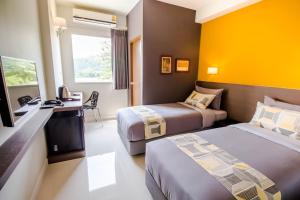 a hotel room with two beds and a television at Fortune D Hotel Loei in Loei