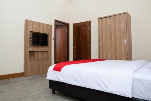 una camera con letto, TV e armadi in legno di RedDoorz Plus near Pasundan University a Bandung