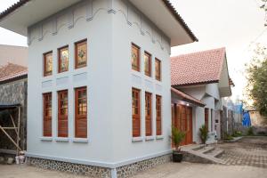 una casa bianca con finestre con persiane rosse di RedDoorz Plus near Pasundan University a Bandung