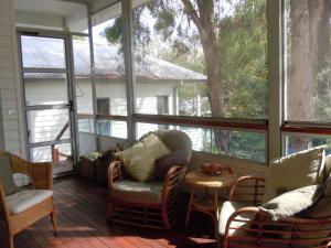 una veranda riparata con sedie, tavolo e finestre di Glenburn House a OʼConnell