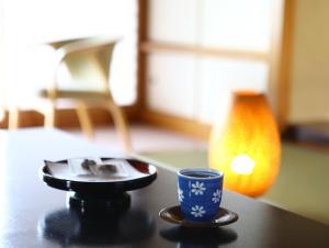 
a coffee cup sitting on top of a table next to a lamp at Kamisuwa Onsen Aburaya Ryokan in Suwa
