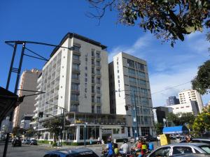 un edificio blanco alto en una calle de la ciudad con coches en Jóia Hotel, en Poços de Caldas