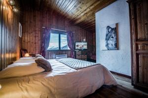 ein Schlafzimmer mit einem großen Bett an einer Holzwand in der Unterkunft Chalet Du Friolin in Les Coches