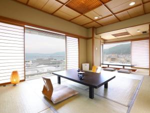 
a living room filled with furniture and a large window at Kamisuwa Onsen Aburaya Ryokan in Suwa
