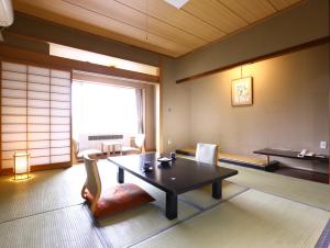 
a living room filled with furniture and a table at Kamisuwa Onsen Aburaya Ryokan in Suwa
