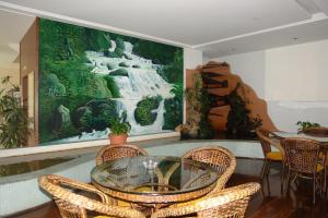 a dining room with a glass table and wicker chairs at Jóia Hotel in Poços de Caldas