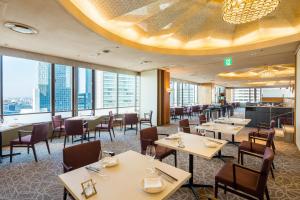 a restaurant with tables and chairs and windows at Meitetsu Grand Hotel in Nagoya