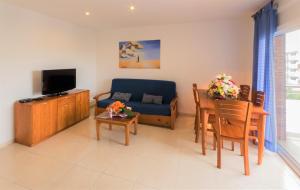 un salon avec un canapé, une télévision et une table dans l'établissement InmoSantos Apartamentos Daniel, à Roses