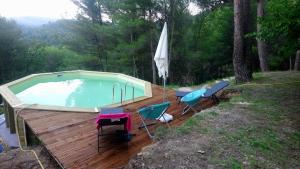 a pool on a wooden deck with chairs and an umbrella at 19 chemin de la carraire in Cadolive
