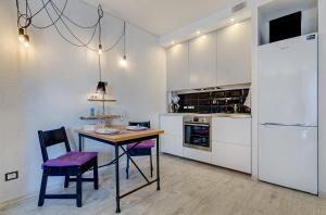 cocina con mesa, sillas y nevera en Black & White Apartment near Akropolis, en Vilna